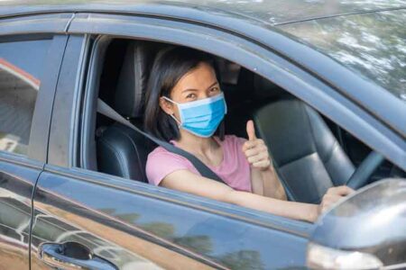 Woman driving car in Indonesia, following road safety guidelines.