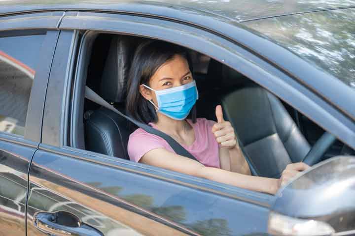 Woman driving car in Indonesia, following road safety guidelines.