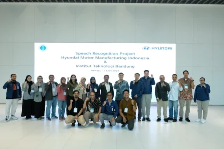 A group photo of participants from the Speech Recognition Project between Hyundai Motor Manufacturing Indonesia and Institut Teknologi Bandung, taken on May 15, 2024, in Bekasi. They are posing in front of a large display screen with the project's title and logos of both organizations.