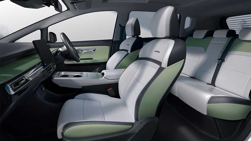 Interior of a GAC Aion Y electric vehicle with two-tone green and white seats, a minimalist dashboard, and a spacious cabin.