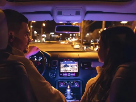 A nighttime interior car view of two people, a man driving and a woman in the passenger seat